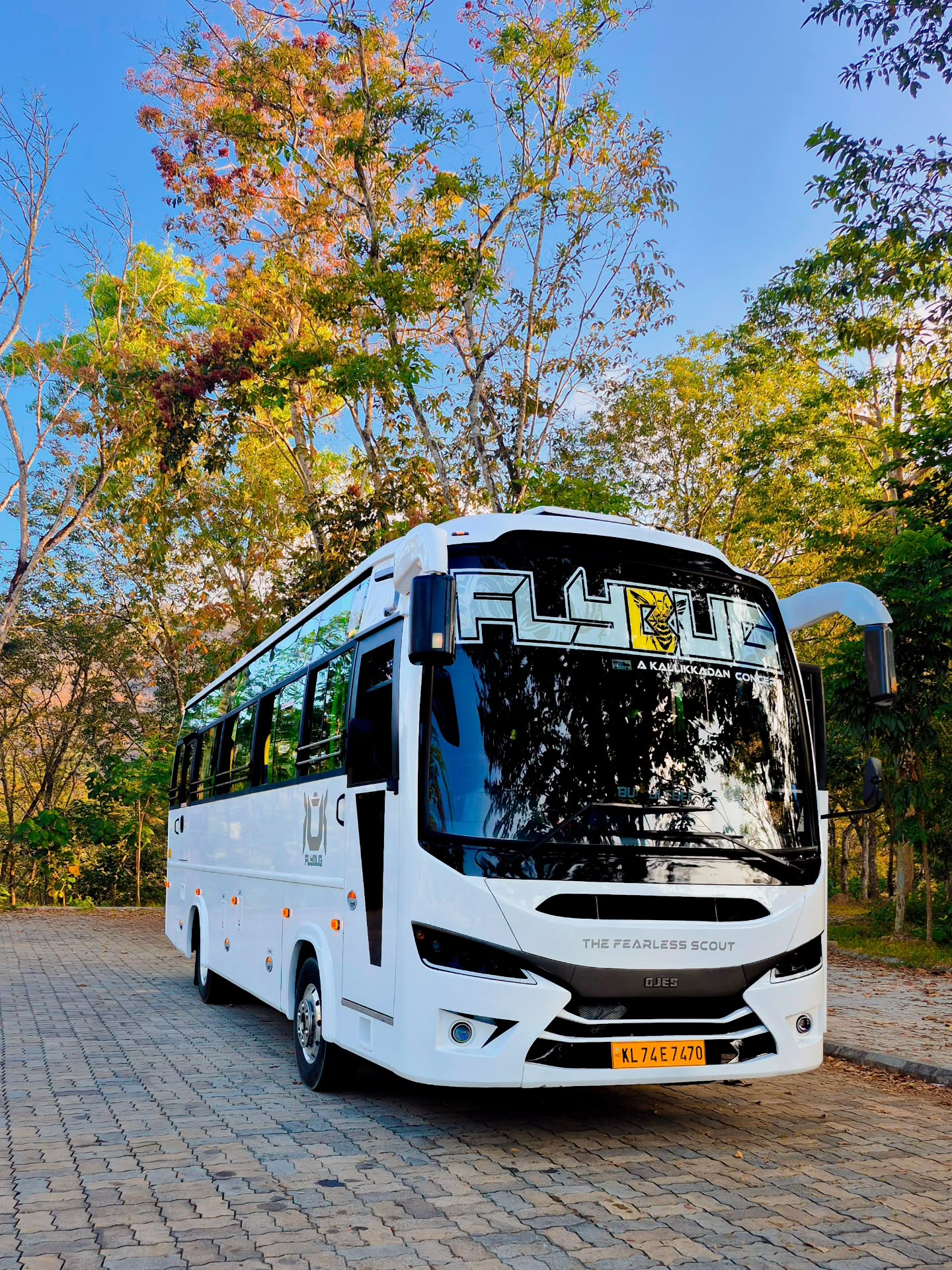 A white JourneyX touring coach on a hill road in warm golden light.