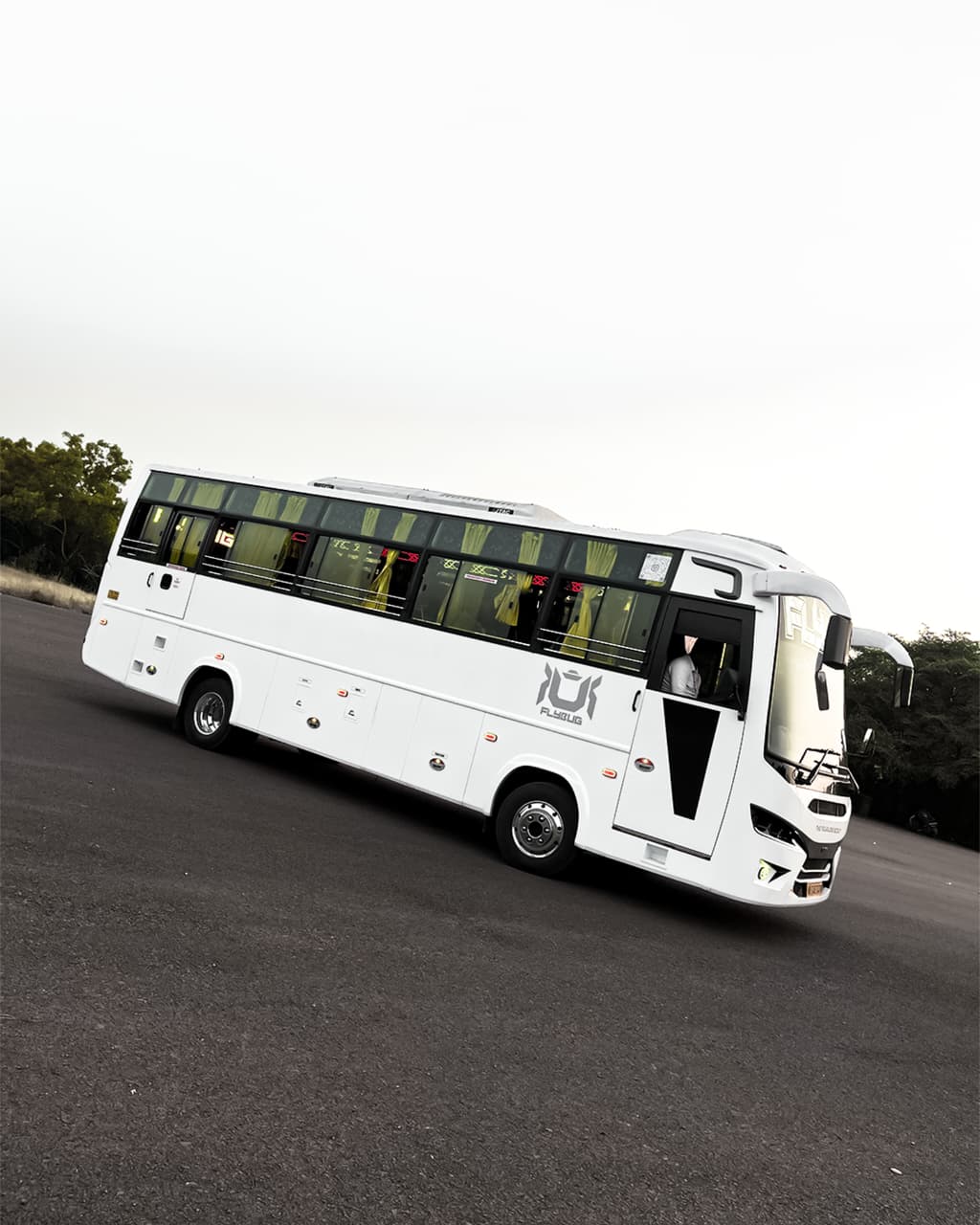 A JourneyX coach with headlights on, travelling a highway in monsoon light.