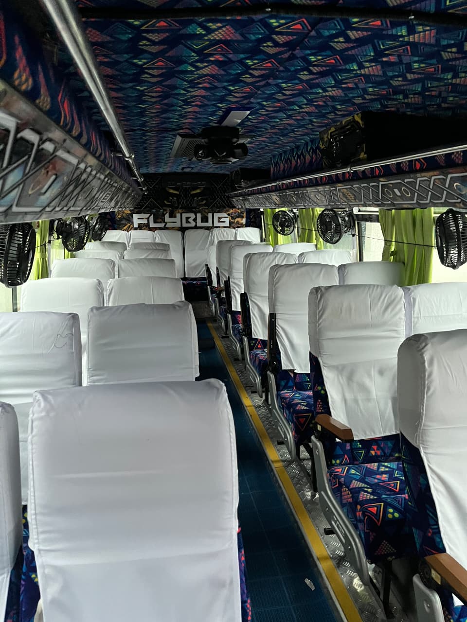 A travel group beside a JourneyX coach on a forest hill road.