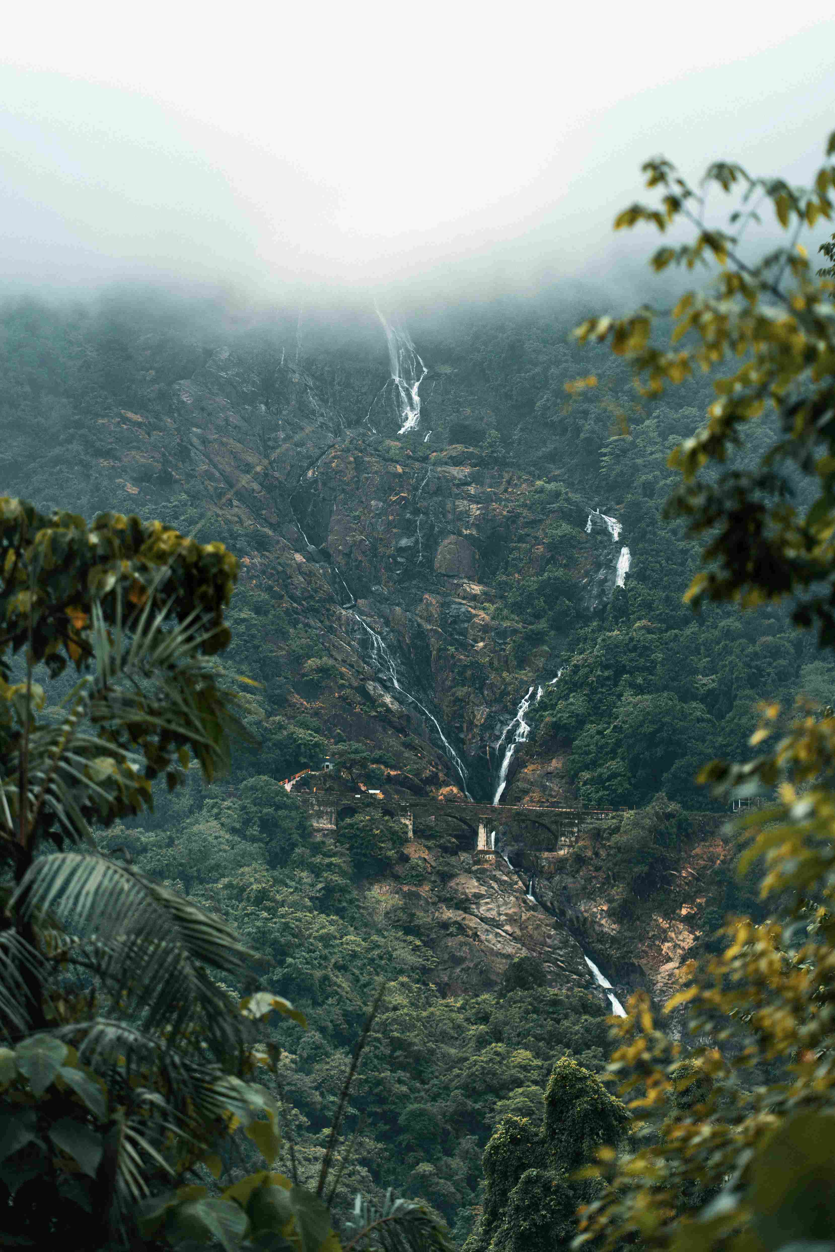 Majestic four-tiered Dudhsagar waterfall with a train track bridge