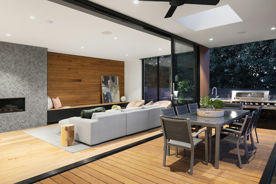 Renovated open-plan living and dining space with timber feature wall opening onto a deck