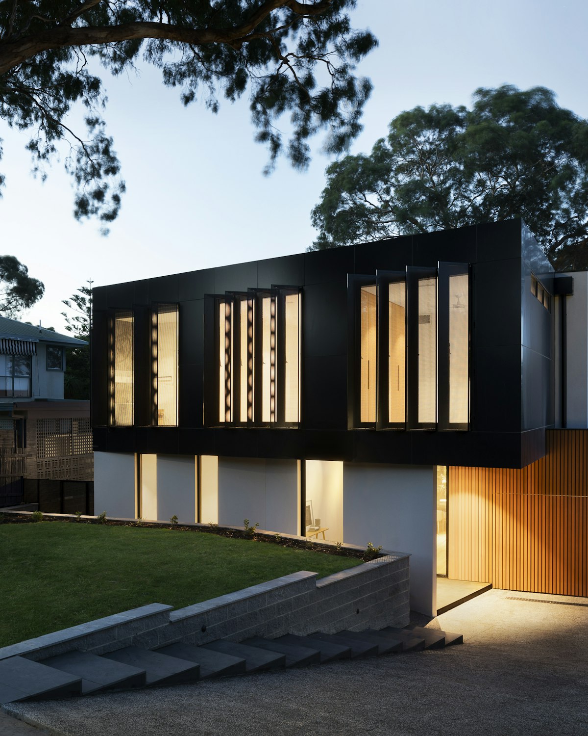Modern residence at dusk with warm light glowing through its full-height windows